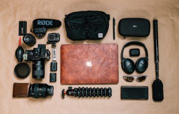 Overhead view of laptop and photo camera composed with headphones and other gadgets of professional photographer